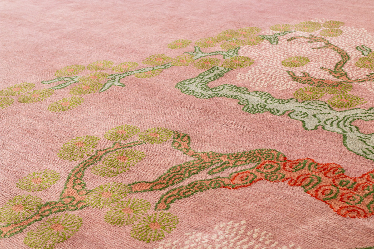 Close-up of a pink fabric with embroidered green and red floral patterns