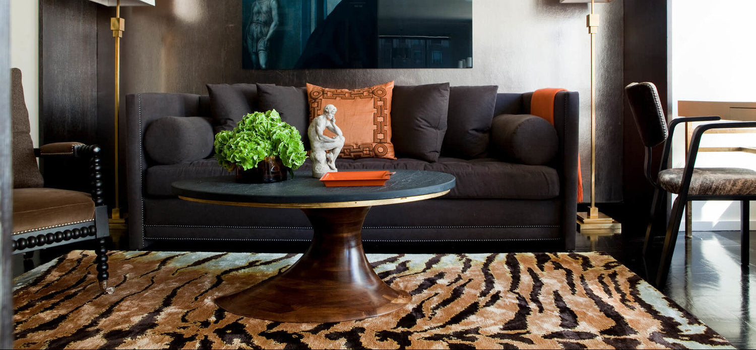 Modern living room with dark gray sofa, round wooden coffee table, and decorative elements.